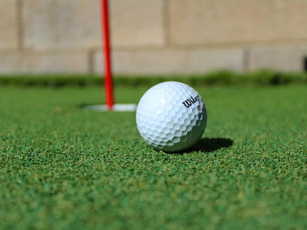 A ball resting beside the hole and a red flagstick